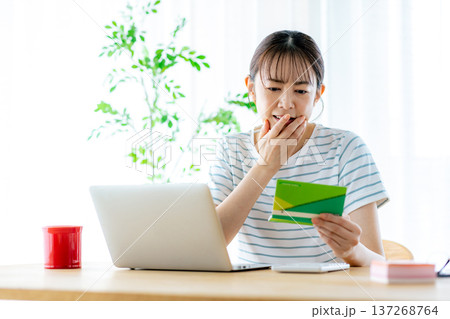 通帳を見てため息をつく主婦 137268764