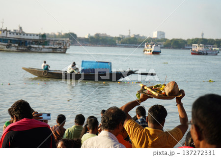 Hindu devotee holding traditional prayer offerings on a bamboo tray over his head during Chhath Puja festival at the river bank Hindu devotee holding traditional prayer offerings on a bamboo tray over his head during Chhath Puja festival at the river bank 137272331