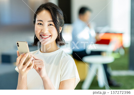 オフィスでスマホを操作するビジネスウーマン オフィスでスマホを操作するビジネスウーマン 137272396