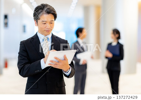 オフィスでタブレットを持って立つビジネスマン 137272429