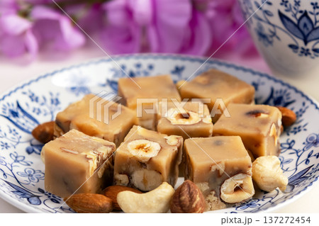 Butter fudge squares with nuts in a saucer with pink wisteria. 137272454