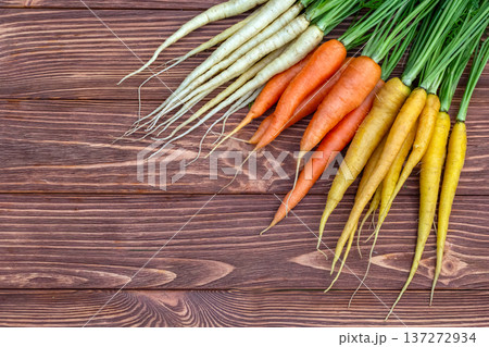 Yellow, orange and white carrots on the brown wooden table. Yellow, orange and white carrots on the brown wooden table. 137272934