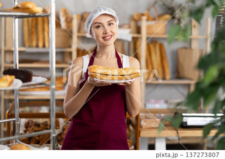 Smiling woman baker offers to buy fresh delicious bocadillo Smiling woman baker offers to buy fresh delicious bocadillo 137273807