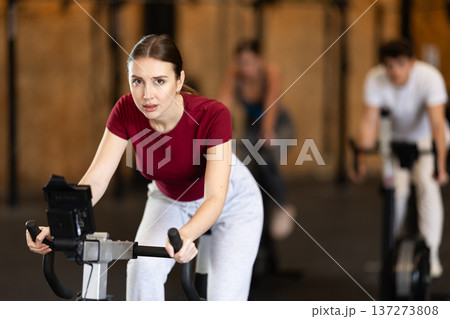 Woman exercising on an exercise bike Woman exercising on an exercise bike 137273808