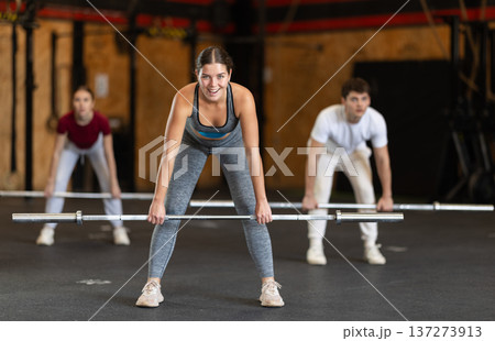 Slender girl trains muscles of arms and back using barbell and differentiated weighting in gym Slender girl trains muscles of arms and back using barbell and differentiated weighting in gym 137273913