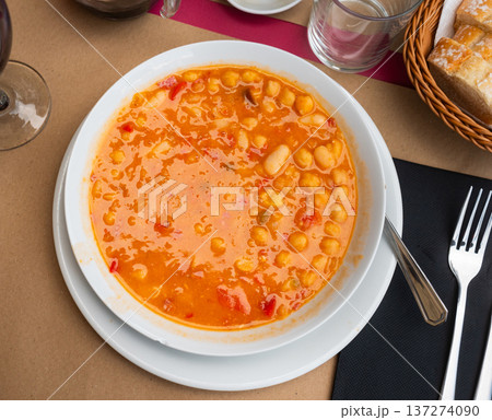 Restaurant serves chickpea and bean soup, served in portions on white plate 137274090