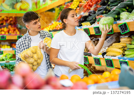 Young husband and wife choose fresh vegetables together in grocery supermarket Young husband and wife choose fresh vegetables together in grocery supermarket 137274195