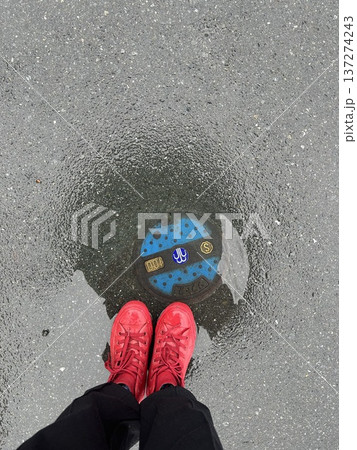 雨の日の水たまりに立つ赤いスニーカーの足元写真 雨の日の水たまりに立つ赤いスニーカーの足元写真 137274243
