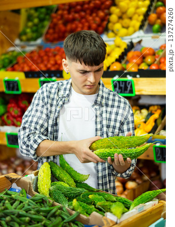 Portrait of man choosing fresh bitter melon in grocery store Portrait of man choosing fresh bitter melon in grocery store 137274260