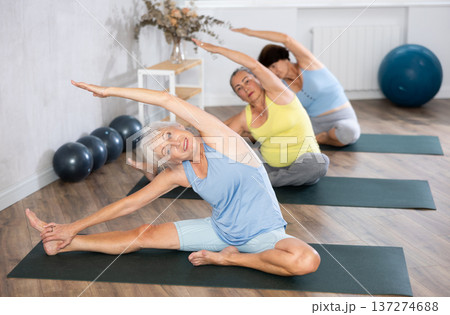 Mature lady performs pose Parivritta janu shirshasana 137274688