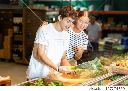 Young woman and young guy choosing leeks in grocery store Young woman and young guy choosing leeks in grocery store 137274729