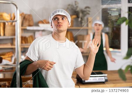 Content young guy leaving his workplace in bakery Content young guy leaving his workplace in bakery 137274903