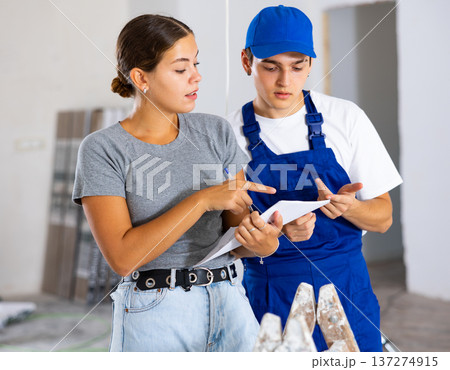 Girl homeowner discussing house renovation work plan with young builder Girl homeowner discussing house renovation work plan with young builder 137274915