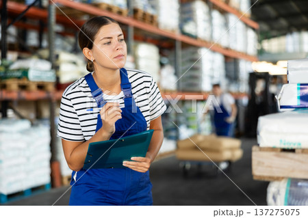 Young woman warehouse worker checking documents Young woman warehouse worker checking documents 137275075