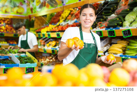 Cheerful young woman selling oranges and fruits in supermarket Cheerful young woman selling oranges and fruits in supermarket 137275108