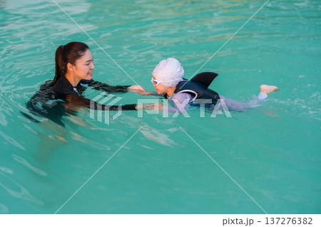 preschool child girl in life jacket learning to swim with mother in swimming pool preschool child girl in life jacket learning to swim with mother in swimming pool 137276382