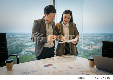 Two coworkers discussing work and pointing at documents of paperwork in meeting room. business people in office 137276440