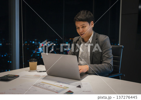 businessman working on laptop computer in business office with city lights background at night businessman working on laptop computer in business office with city lights background at night 137276445