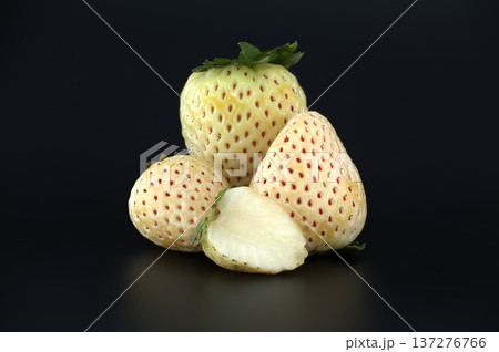 Unique pineberry strawberries with red seeds displayed on a dark background Unique pineberry strawberries with red seeds displayed on a dark background 137276766