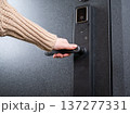 A woman opens a modern smart door lock with a digital keypad and biometric fingerprint access. 137277331