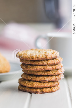 Fresh oatmeal cookies on a white table with a blurred background showing a cozy setting in a kitchen 137278180
