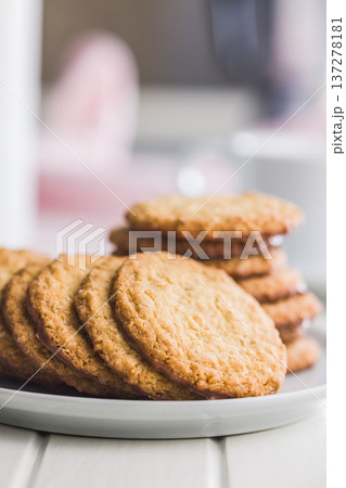 Fresh oatmeal cookies on a plate with a blurred background showing a cozy setting in a kitchen 137278181