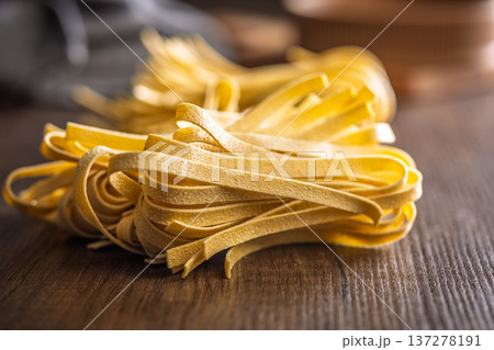 Fresh pasta ready for cooking, showing strands of fettuccine set on a wooden table. 137278191