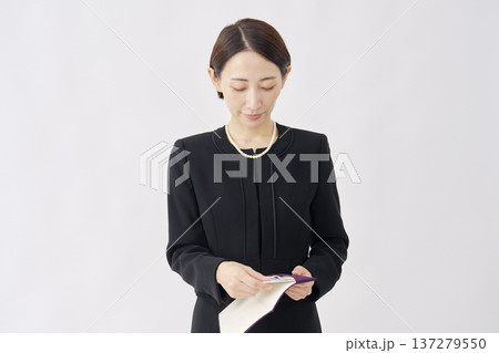 袱紗から香典を出す喪服を着た女性　白背景 137279550