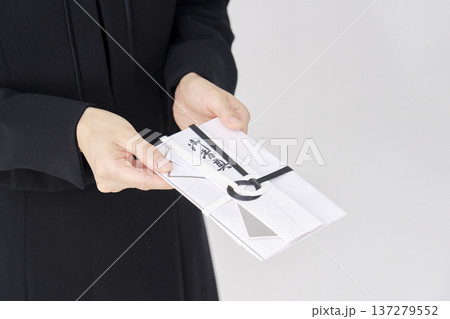 香典を渡す喪服を着た女性　白背景　顔無し 137279552