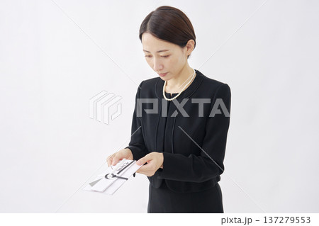 香典を渡す喪服を着た女性 白背景 香典を渡す喪服を着た女性 白背景 137279553