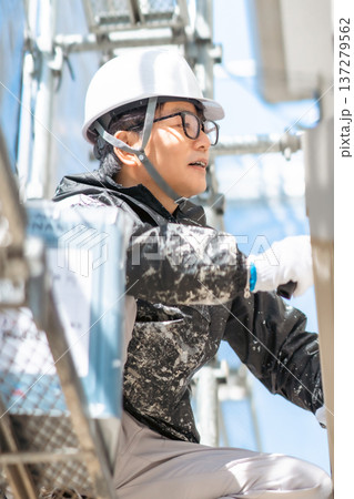 危険が高所で3度塗りを行うヘルメット姿の男性作業員 危険が高所で3度塗りを行うヘルメット姿の男性作業員 137279562