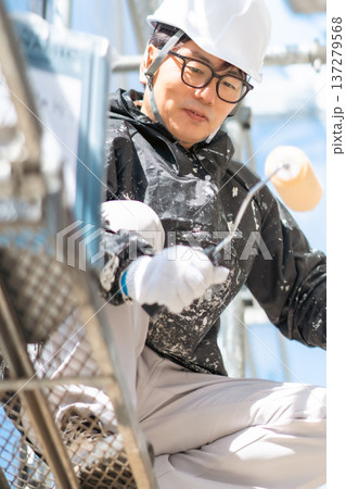 危険が高所で3度塗りを行うヘルメット姿の男性作業員 危険が高所で3度塗りを行うヘルメット姿の男性作業員 137279568