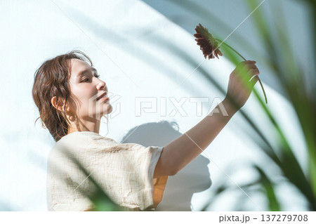 一輪のガーベラの花を持つ,見つめる女性 137279708
