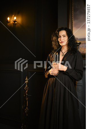 Person holds candle in dark room with art on wall and candlelight illuminating space at night Person holds candle in dark room with art on wall and candlelight illuminating space at night 137279857