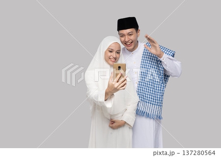 Couple capturing special family moment. Asian Muslim couple sharing joyful photo together Couple capturing special family moment. Asian Muslim couple sharing joyful photo together 137280564