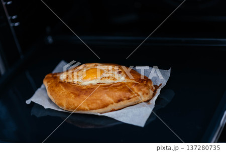 Khachapuri on baking paper is baked in the oven. We cook khachapuri with our own hands at home. Delicious quick dishes Khachapuri.  137280735