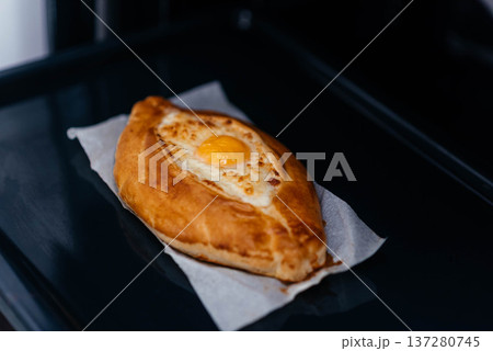 Khachapuri on baking paper is baked in the oven. We cook khachapuri with our own hands at home. Delicious quick dishes Khachapuri.  137280745