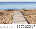 A weathered wooden boardwalk crosses warm sand 137282217