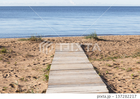 A weathered wooden boardwalk crosses warm sand 137282217