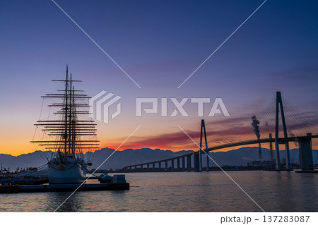 夜明けの海王丸パークから朝焼けの立山連峰を背景に新湊大橋と海王丸 137283087