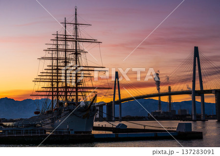 夜明けの海王丸パークから朝焼けの立山連峰を背景に新湊大橋と海王丸 137283091