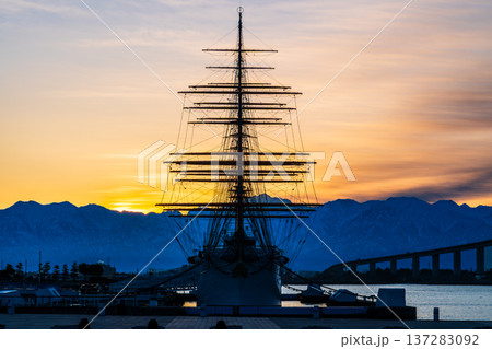 夜明けの海王丸パークから朝焼けの立山連峰を背景に新湊大橋と海王丸 137283092