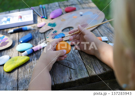 Young artists create colorful scenes on smooth pebbles, crafting unique handmade gifts for loved ones. Young artists create colorful scenes on smooth pebbles, crafting unique handmade gifts for loved ones. 137283943