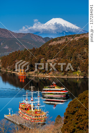 朝の芦ノ湖に浮かぶ遊覧船と雪をかぶった富士山 137284041