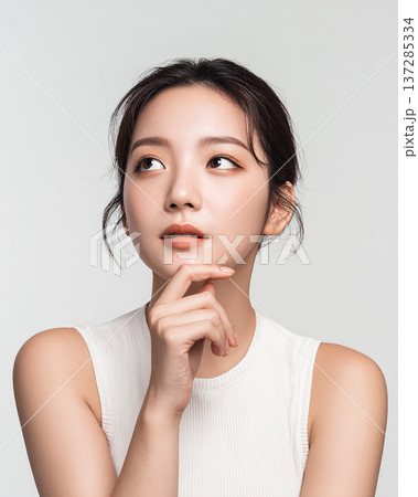 指を顎に添えて微笑む女性モデル 健康的な肌とナチュラルな美しさ 137285334