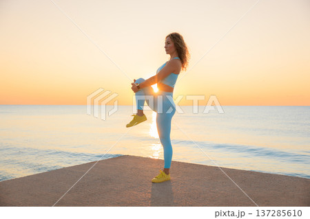 Sporty young woman is stretching against sea background during her vacation. Freedom and summer sport concept 137285610