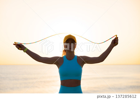 Fit woman jumping rope at the beach during summer vacation 137285612