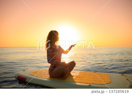Young woman walking on sup board by the sea during summer vacation Young woman walking on sup board by the sea during summer vacation 137285619
