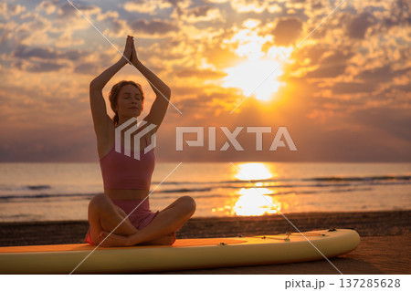 Athlete woman practicing yoga at the beach during summer vacation. Slow motion 137285628