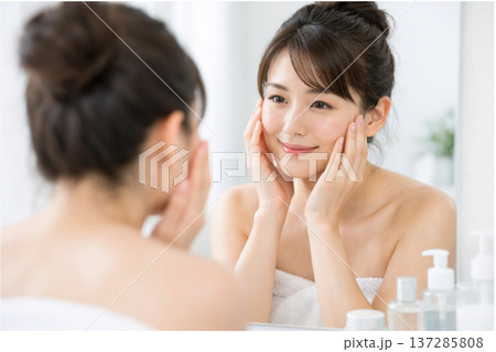 明るい洗面所で鏡を見ながら肌の状態をチェックする日本人女性 137285808
